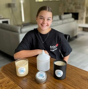 Kenzie's Candles owner Mackenzie Robinson poses with her candles in a Rosies - Friends on the Street supporter shirt